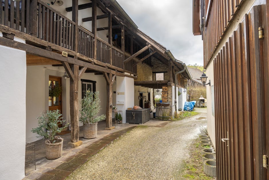 Charming rustic courtyard featuring a traditional wooden house with plants and open walkway.