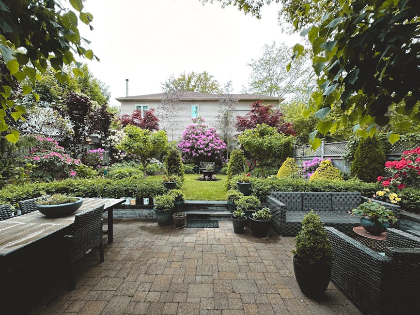 A tranquil backyard garden showcasing vibrant flowers, lush greenery, and patio furniture.